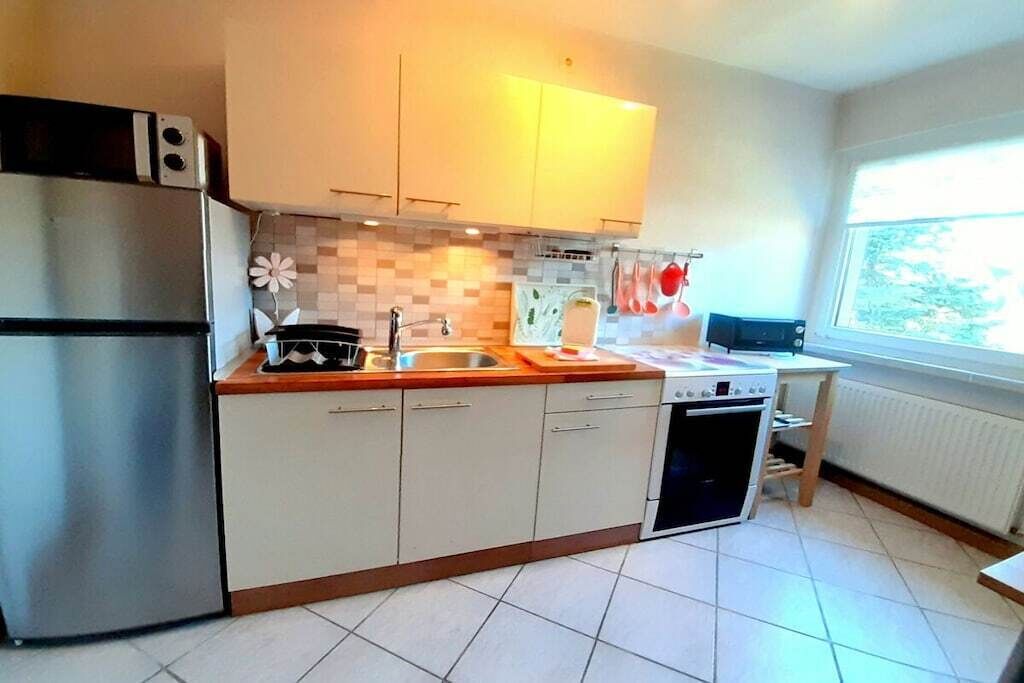 A kitchen with a refrigerator, stove, sink, and window.