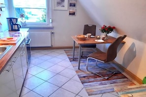 A kitchen with a dining table, chairs, a coffee maker, and a window with a view. - Holiday apartment in Born with swimming pool (Born)