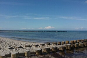 Een strand met een houten steiger en een pier die het water in reikt.