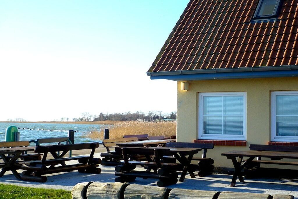 Een gebouw met een pannendak, een raam met zonwering, en een picknickplaats met banken.