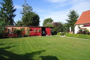 A red building with a door and windows, surrounded by a well-maintained lawn and trees. - Holiday apartment in Born with swimming pool (Born)