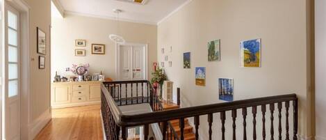 A hallway with wooden flooring, a staircase with black balusters, and a ceiling with a skylight.