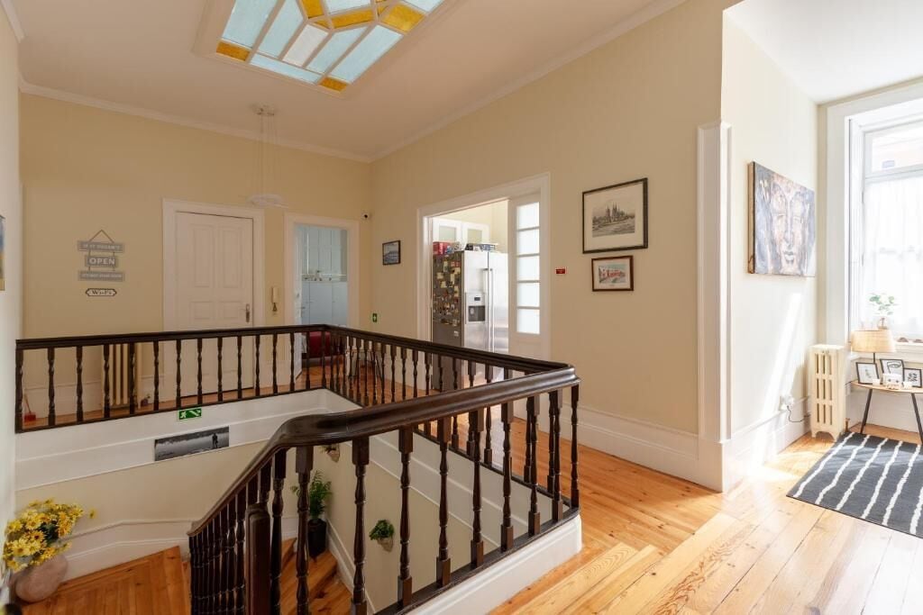 Une pièce spacieuse avec un escalier en bois, un luminaire au plafond et une porte donnant sur une autre pièce.