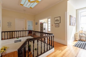 Una habitación amplia con una escalera de madera, una lámpara en el techo y una puerta que da a otra estancia.