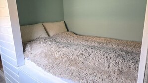 Una stanza con un letto, una parete verde chiaro e un davanzale bianco.