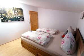 Ein Schlafzimmer mit einem hölzernen Bett, einer Tür und einem an der Wand befestigten Bild.