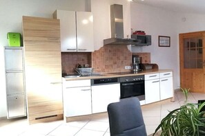 A modern kitchen with white cabinetry, a built-in oven, and a dishwasher. - Holiday apartment with 1 bedroom (Götzens)
