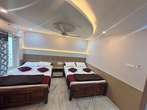 A hotel room with two single beds, a ceiling fan, and a nightstand between them. - Azhagar Residency (Tiruvannamalai)