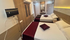 Una camera d'albergo con due letti, una televisione, un condizionatore d'aria e una ventola a soffitto.