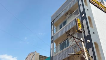 Un immeuble à plusieurs étages portant les enseignes « AZHGAR RESIDENCY » et « ROOMS ».