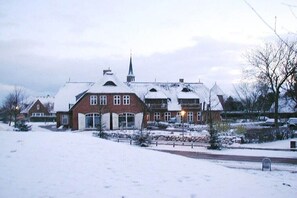 Ein großes Gebäude mit zahlreichen Fenstern und einem markanten Turm, umgeben von verschneitem Gelände.
