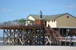 Eine Holzstege zu einem Gebäude mit grüner Dach und einer Flagge.