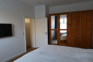 Ein Schlafzimmer mit einem Bett, einem Kleiderschrank und einem Fernseher an der Wand.