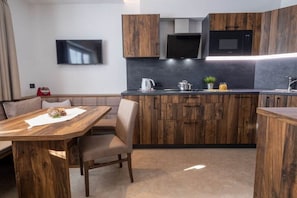 A modern kitchen with wooden cabinets, a built-in microwave, and a flat-screen TV.