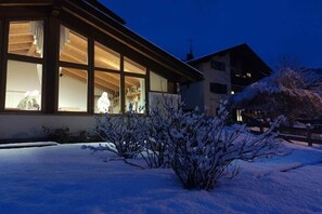 A building with large windows, a wooden facade, and snow-covered ground.