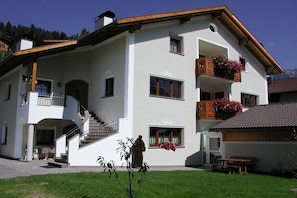 A two-story building with a balcony, a staircase, and a small garden area.