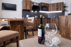 A modern kitchen with wooden cabinets, a flat-screen TV, and a dining area with a bench and table.