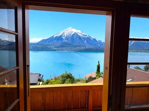 Un balcon en bois offrant une vue sur une montagne et un lac.