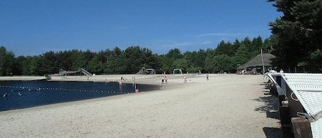 A beach with a clear sky, a sandy shore, and a row of beach huts.