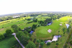An aerial view of a golf course with multiple holes, water hazards, and a surrounding landscape. - Holiday apartment with 1 bedroom (Wiesmoor)