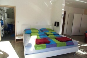 A modern bedroom with a bed, a small bedside table, a wardrobe, and a bathroom visible in the background. - Holiday apartment with 1 bedroom (Wiesmoor)