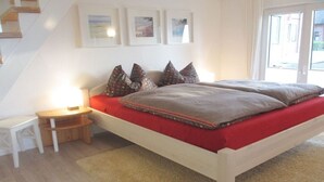 A bedroom with a bed, bedside table, and a window. - Holiday home with 2 bedrooms (Varel - Dangast)