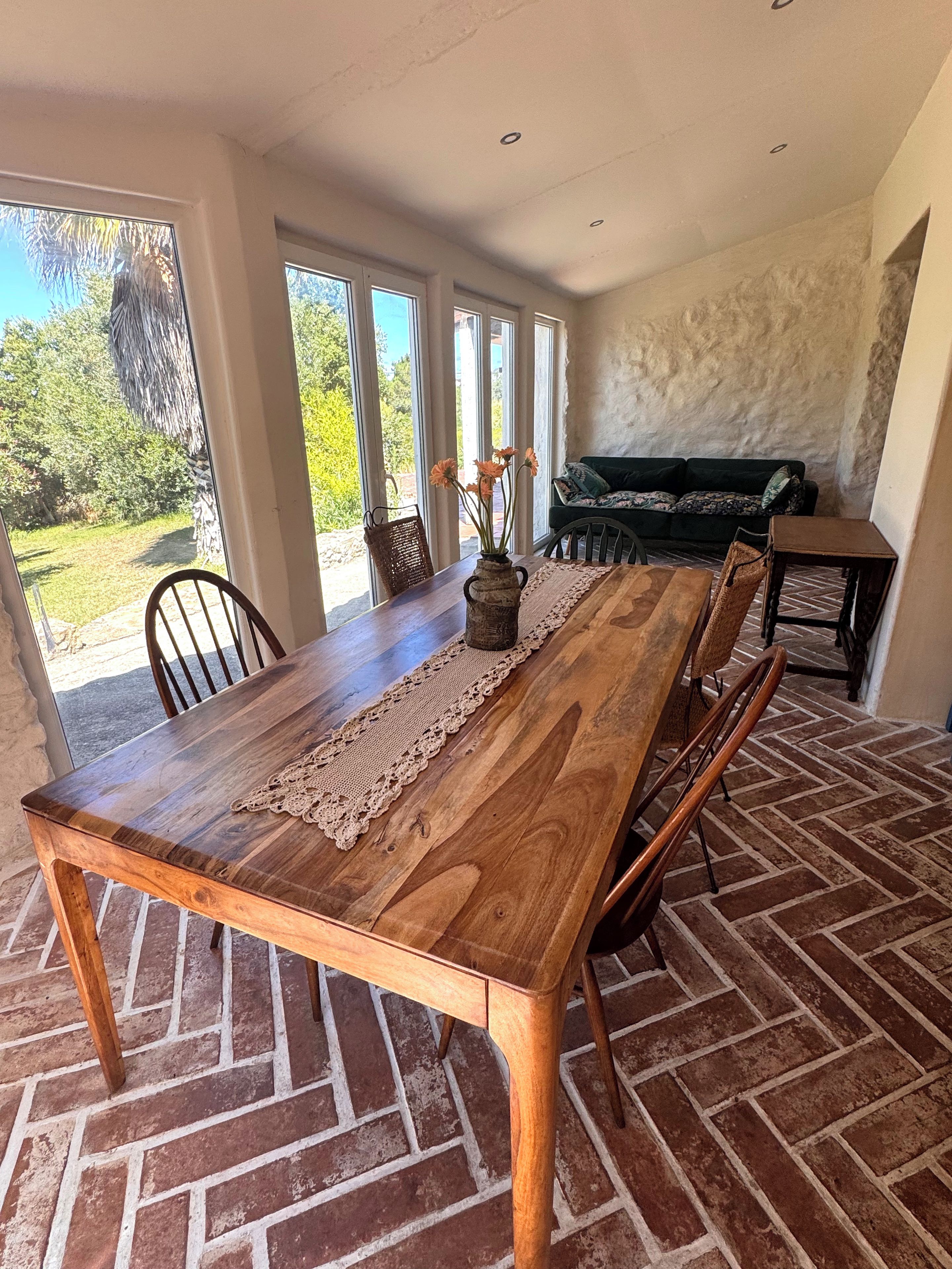 A dining area with a wooden table, chairs, and a vase of flowers.