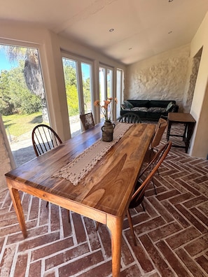 A dining area with a wooden table, chairs, and a vase of flowers. - Country house near the city, peace and quiet, nature, a pool, and a spacious garden. (Bucelas)