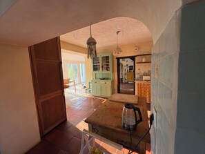 A spacious kitchen with a wooden table, a kettle, and a hanging light fixture. - Country house near the city, peace and quiet, nature, a pool, and a spacious garden. (Bucelas)
