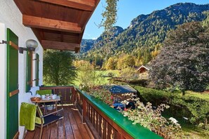 Eine Holzterrasse mit Tisch und Stühlen, mit Blick auf eine gebirgige Landschaft.