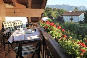 An outdoor dining area with a table set for two, surrounded by chairs with checkered cushions. - Holiday apartment with 1 bedroom (Sonthofen)