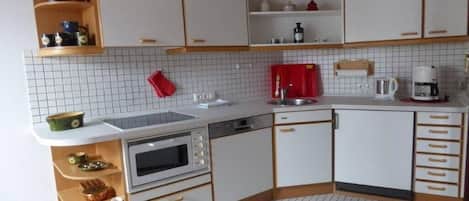 A compact kitchen with white cabinets, a microwave, a sink, and a coffee maker.