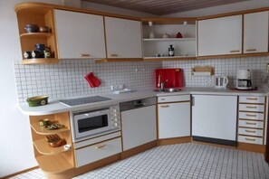 A compact kitchen with white cabinets, a microwave, a sink, and a coffee maker. - Holiday apartment with 1 bedroom (Sonthofen)