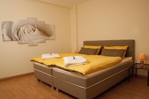 A bedroom with a bed, pillows, a bedside table, and a wall art piece. - Holiday apartment with 1 bedroom (Grünendeich)