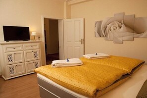 Een hotelkamer met een bed, een televisie op een dressoir en een deur naar een andere kamer.