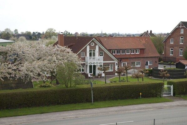 Een woongebouw met een symmetrische gevel, een centrale ingang met een witte deur en een klein balkon.