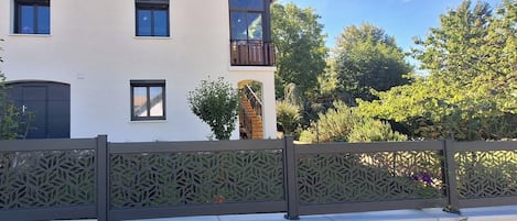 Un bâtiment à deux étages doté d’un balcon, d’un escalier et d’une clôture décorative.