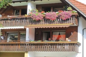 A two-story building with a balcony adorned with hanging flower baskets. - Holiday apartment with 2 bedrooms (Lenzkirch)