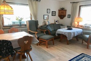 Een eethoek met een tafel, stoelen, een lamp en een raam met gordijnen.