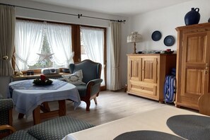 A cozy room with a dining table, a chair, a cabinet, and a window with curtains. - Holiday apartment with 2 bedrooms (Lenzkirch)