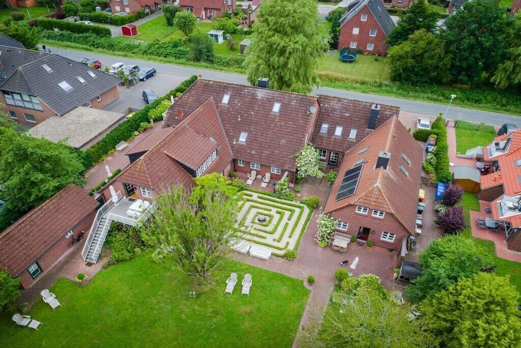 Un quartier résidentiel comprenant plusieurs maisons, un jardin central avec un labyrinthe et un petit bâtiment doté d’un escalier.