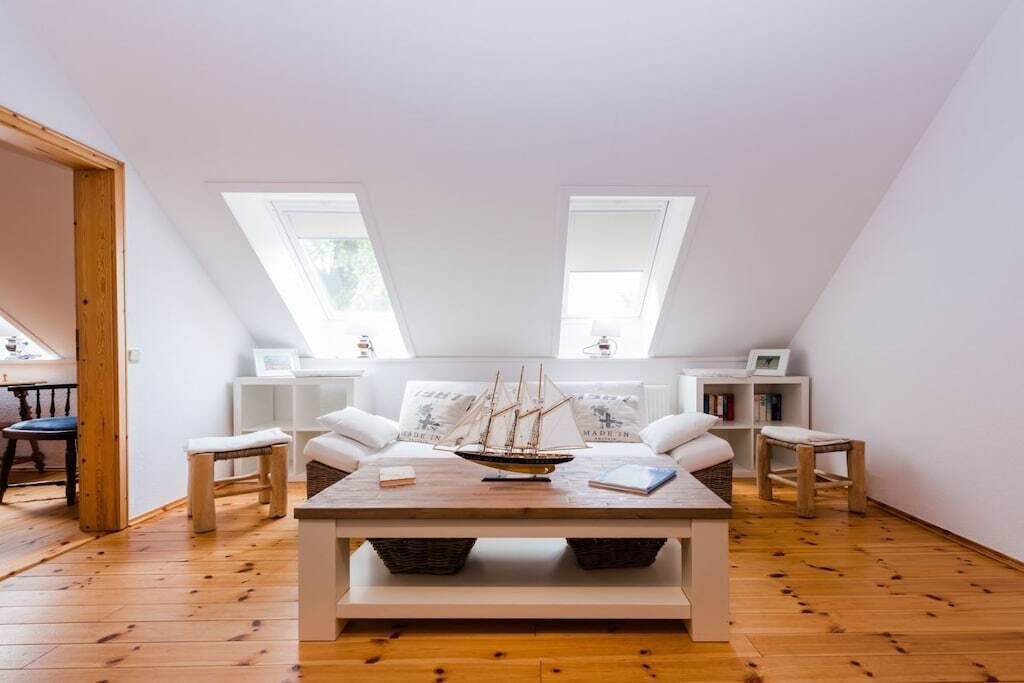 Habitació amb terra de fusta, taula central amb model de vaixell, sofàs blancs i dos ulls de búfals.
