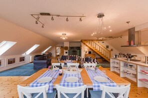 Un vaste loft comprenant un espace repas, une cuisine et un escalier.
