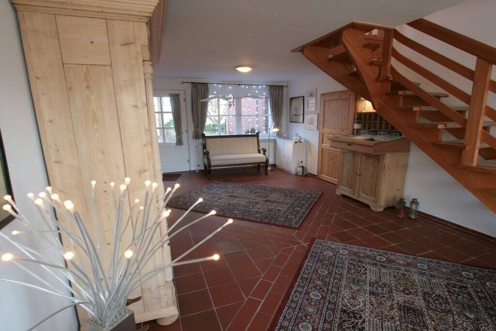 Une pièce spacieuse avec un escalier en bois, un lit, une fenêtre avec des rideaux et un tapis.