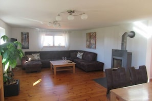 Ein Wohnzimmer mit Kamin, einer Couch, einem Couchtisch und einem Esstisch mit Stühlen.