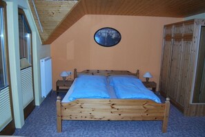 Ein Schlafzimmer mit einem hölzernen Bett, zwei Nachttischlampen, einem runden Spiegel an der Wand und einer Heizung.