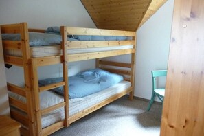 En våningssäng med tre våningar, ett träpanelat tak och en ljusblå vägg.