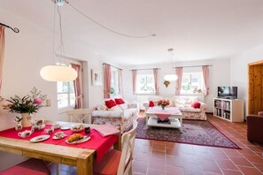 Ein geräumiges Wohnzimmer mit Essbereich, Fernseher und Bücherregal.