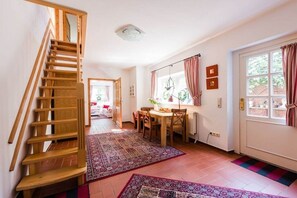 Eine Treppe führt zu einer oberen Etage, ein Essbereich mit Tisch und Stühlen sowie eine Tür mit Fenster.