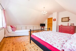 Une chambre à coucher avec un lit, une commode, un téléviseur et un lustre.